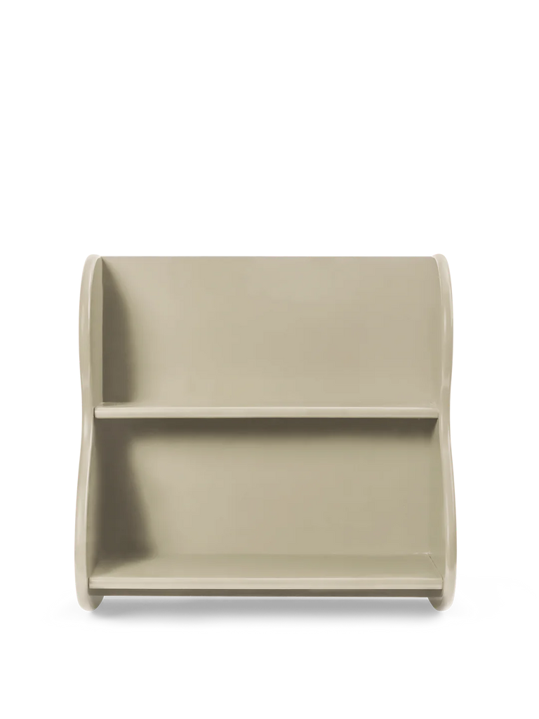 A minimalistic, modern Ferm Living Slope Shelf - Cashmere in a light beige color, set against a black background. The shelf has a rounded, rectangular shape with a visible cord and is constructed from F
