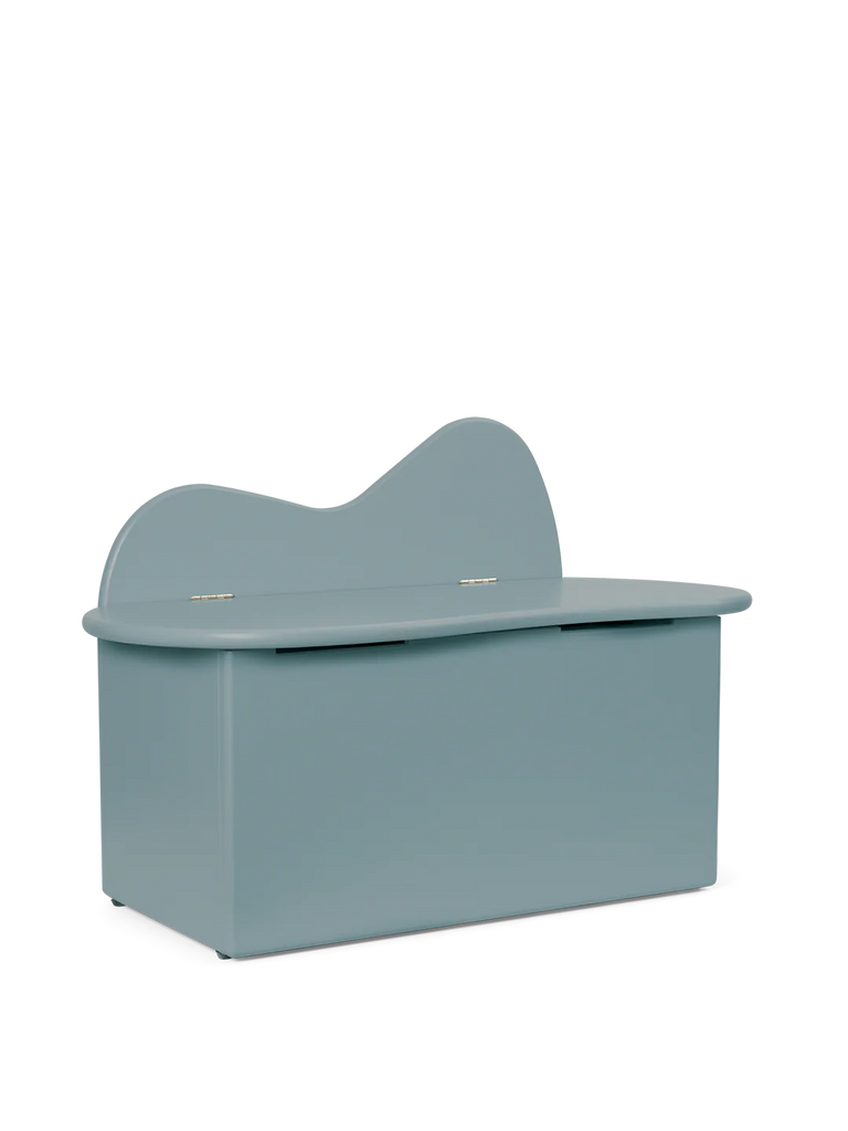 A light blue grand piano with the lid open and a matching Ferm Living Slope Storage Bench - Storm, isolated on a dark background.