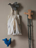 A canvas drawstring bag with a simple geometric design hanging on the Ferm Living hand-carved wooden bird hook, flanked by colorful bird-shaped wall decorations in black and blue, against a neutral-toned backdrop.