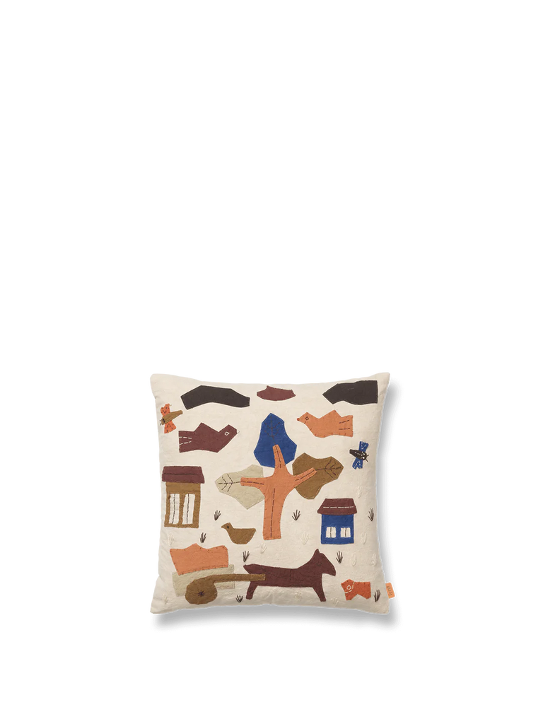 A handmade appliqué cushion with a minimalist, hand-embroidered design featuring abstract shapes, a dog, houses, trees, and a cart in various earthy tones such as brown, orange, blue, and beige. The light-colored background enhances the intricate details of this Ferm Living Village Cushion - Off-White GOTS certified organic cotton piece.