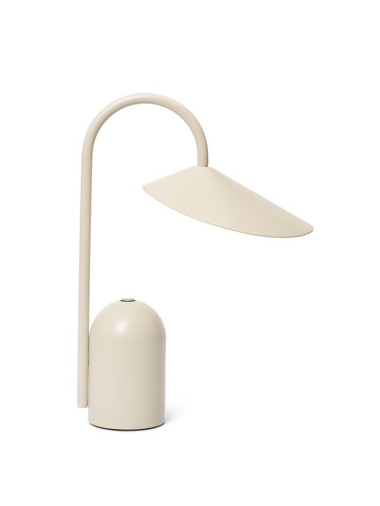 The Ferm Living Arum Portable Lamp in Cashmere features a modern, minimalist design with a curved stem and wide dome-shaped shade, all in cream, shown against a plain white background.