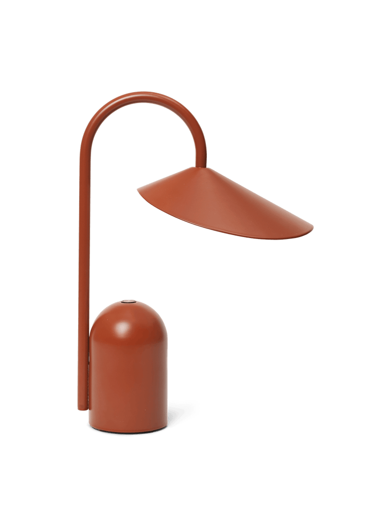 The Ferm Living Arum Portable Lamp in red features a modern design with a curved metal arm and wide, cone-shaped shade, touch dimmable functionality, and is shown against a plain white background.