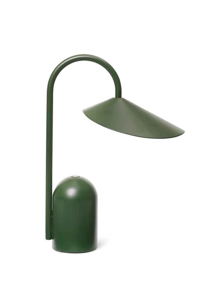 The Ferm Living Arum Portable Lamp in grass green features a modern matte finish, a curved stem, and a wide, angled cone-shaped shade, shown against a plain white background.