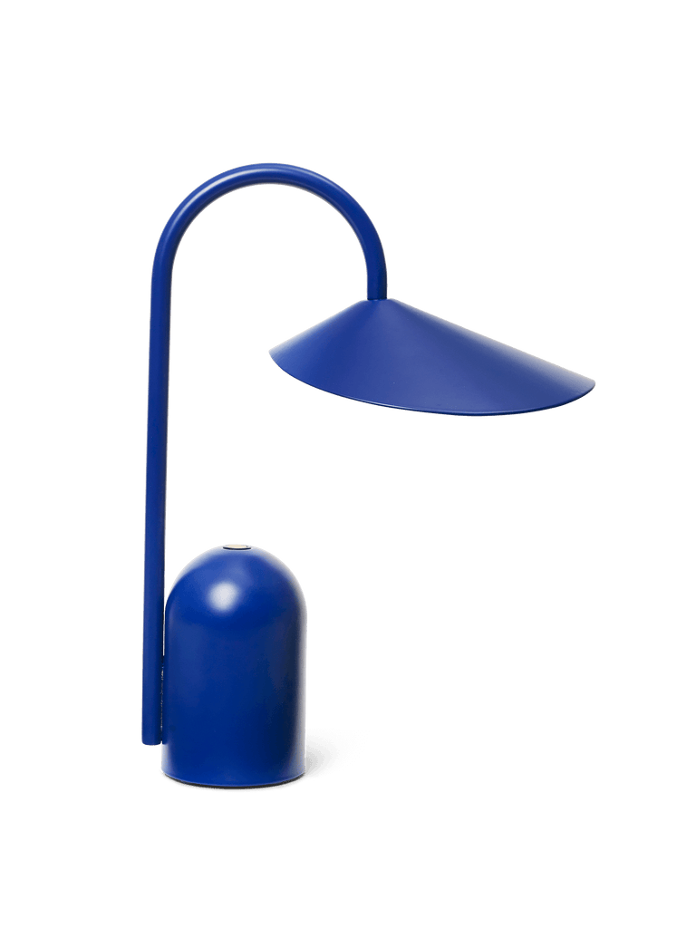 The Ferm Living Arum Portable Lamp in blue features a curved stem and wide, slanted shade on a rounded cylindrical base, shown against a plain white background.