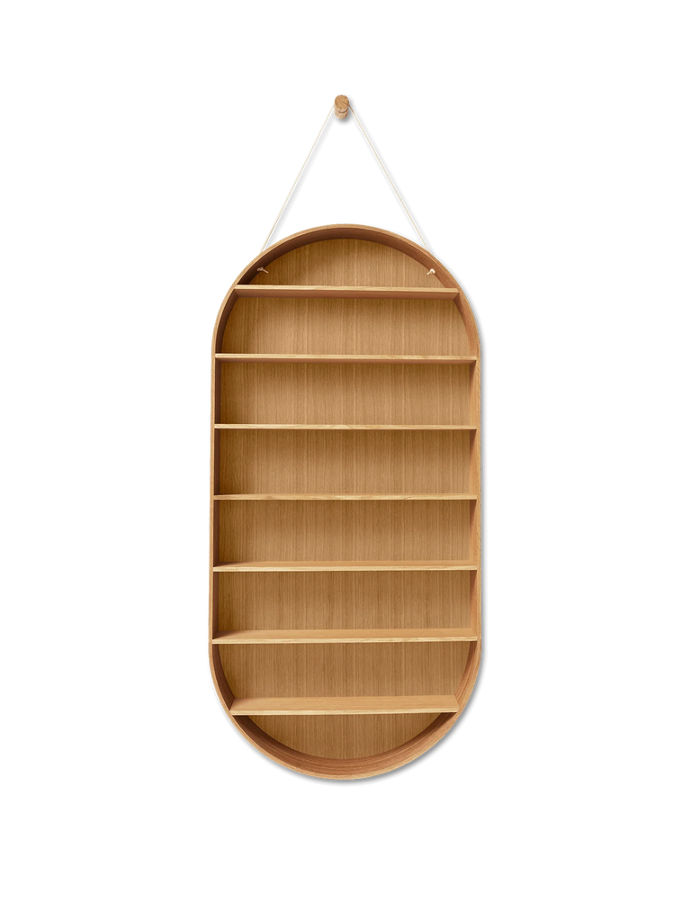 The Ferm Living Oval Oak Dorm Shelf features a minimalist, oval design with multiple horizontal compartments, suspended by a string from a single hook against a black backdrop—modern storage furniture at its finest.