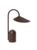 The Ferm Living Arum Portable Lamp in Dark Chocolate features a modern, minimalist design with a curved stand and an angled, wide lampshade, shown against a plain white background.