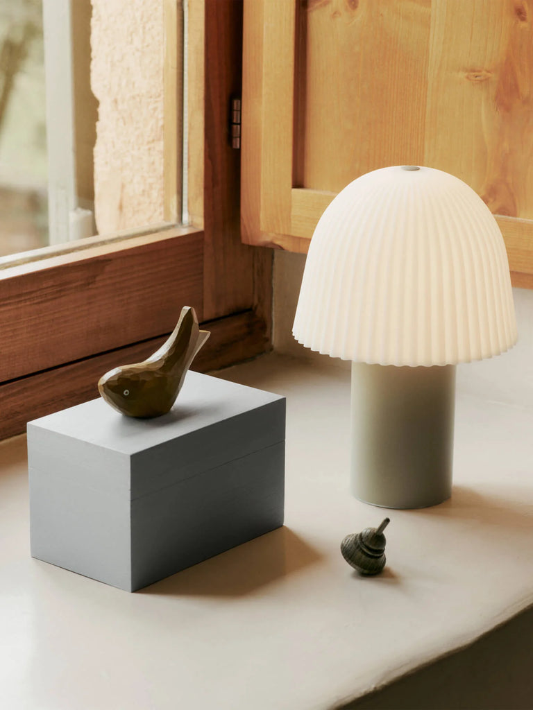 The Ferm Living Hand Carved Wooden Harbour Box - Fish sits on a windowsill with FSC certified aspen wood frames, next to a ceramic bird figurine, a small decorative object, and a white lamp with a pleated shade.
