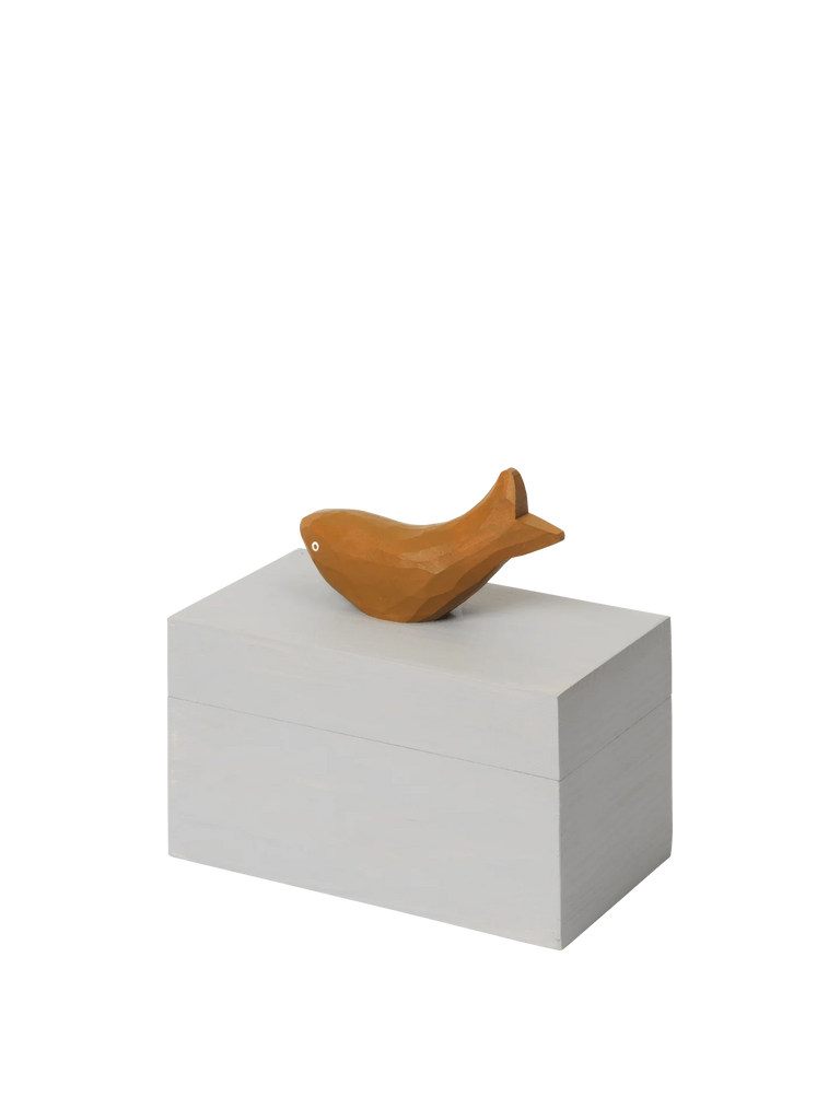 The Ferm Living Hand Carved Wooden Harbour Box - Fish features a small, wooden fish figurine atop a plain, hand-carved box—a charming decor piece perfect for a child's room.