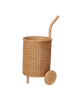 The Ferm Living Tukki Trolley - Natural, a cylindrical wicker rattan storage trolley with a curved handle and two wooden wheels, stands upright against a plain white background.