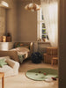 A cozy children's bedroom with a small bed, plush toys, wicker baskets, a star-patterned ball, and sunlight through sheer curtains—complete with the Ferm Living Apple Tufted Rug in Tea Green for extra comfort.