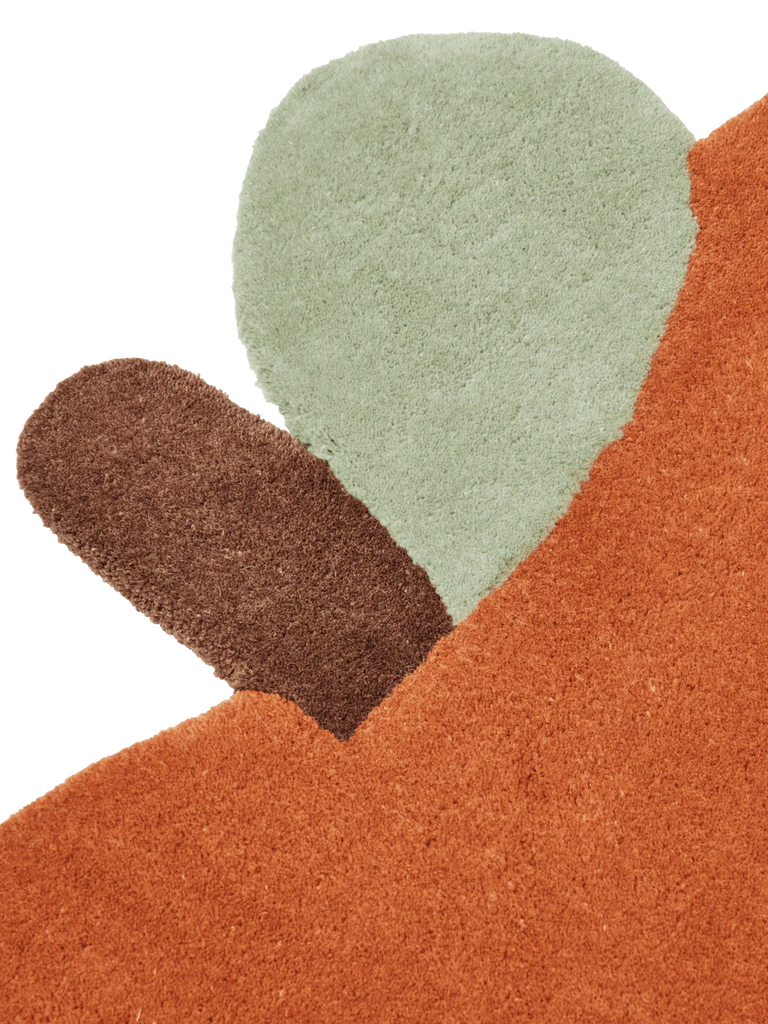 The Ferm Living Apple Tufted Rug - Brown Clay is a textured New Zealand wool rug with an abstract rust-orange shape, a small green oval, and a brown oval—ideal for brightening up any kids' playroom.