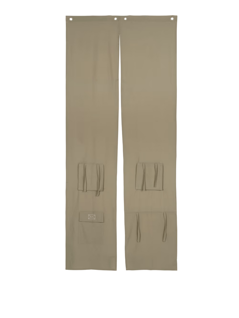 Two long, rectangular panels in elm green fabric, crafted from recycled cotton, each featuring pockets and ties as well as two holes at the top for easy hanging. These versatile Ferm Living Settle Door Curtain panels can be used as a door curtain or a kids’ play curtain and are displayed side by side on a white background.