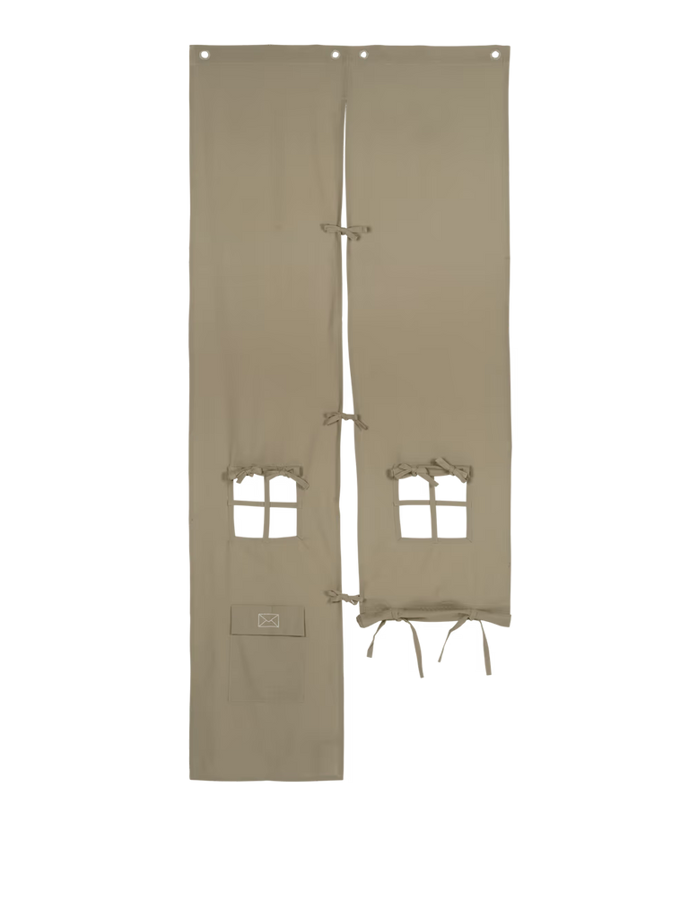 Two elm green fabric panels, known as the Ferm Living Settle Door Curtain, crafted from recycled cotton and featuring cut-out window shapes with tie closures, resemble a kids’ play curtain or theatrical backdrop against a white background.