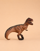 A brown plastic Schleich Giganotosaurus Large Dinosaur Toy with a movable jaw stands with its mouth open, displaying sharp teeth, against a plain beige background. This detailed model captures the fierce appearance of a classic dinosaur collectible and reflects the high quality of Schleich toys.