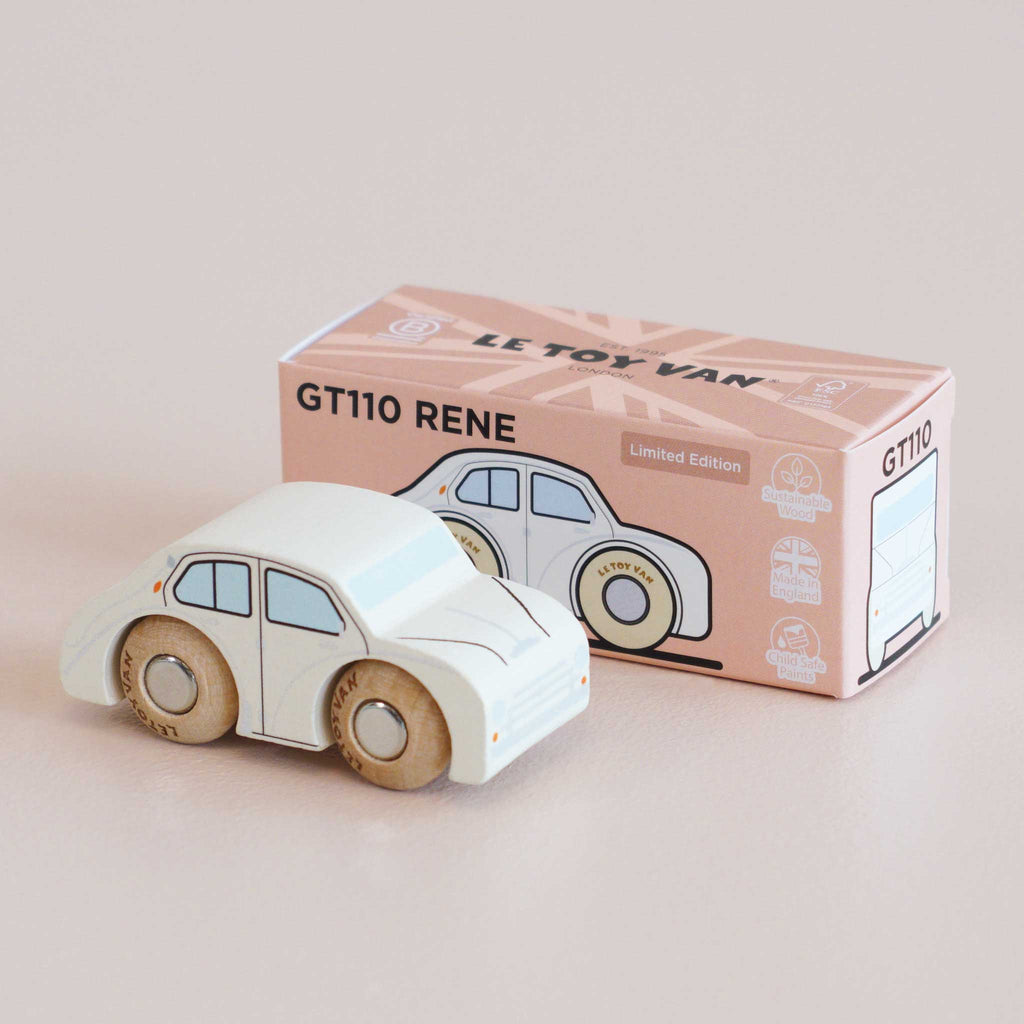 A small white wooden toy car with natural wood wheels sits beside its pink and white box labeled “No. 20 GT110 Rene | Made in England.” This classic toy features minimal detailing and is perfect for imaginative play.