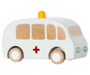 The Maileg Wooden Ambulance is a charming toy featuring solid wood construction, white paint with a red cross on the side, four wooden wheels, and a small yellow light on top. Its natural wood color windows and push or pull-back function offer delight.