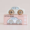 A classic toy for imaginative play, the No. 20 GT110 Rene—a white wooden car with brown wheels—sits atop a pink box labeled “GT110 RENE.” The box displays a drawing of the car along with icons indicating sustainable wood and child-safe paint, and proudly notes it is made in England.