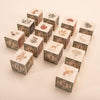 Uncle Goose Watercolor ABC Blocks offer an eco-friendly collection of basswood alphabet blocks adorned with vibrant paintbox designs, showcasing enchanting illustrations of animals and nature—such as bears, deer, and bees—set against a light background in a charming staggered arrangement.