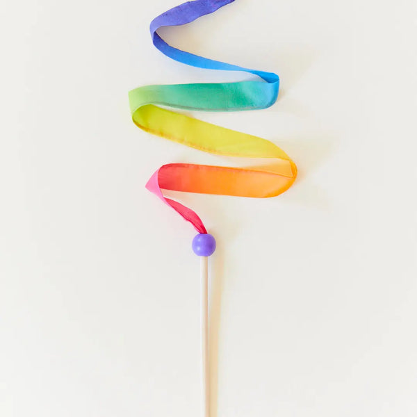 A Sarah's Silk Mini Rainbow Streamer Wand with a purple ball at the end, featuring ribbons in blue, green, yellow, orange, and pink, gracefully swirling against a white background.