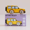A yellow wooden 4x4 toy SUV rests atop a purple box labeled “No. 35 GT195 Riley | Made in England.” The box features an illustration matching the adventure vehicle, along with icons for sustainable wood, made in England, and child-safe paints.