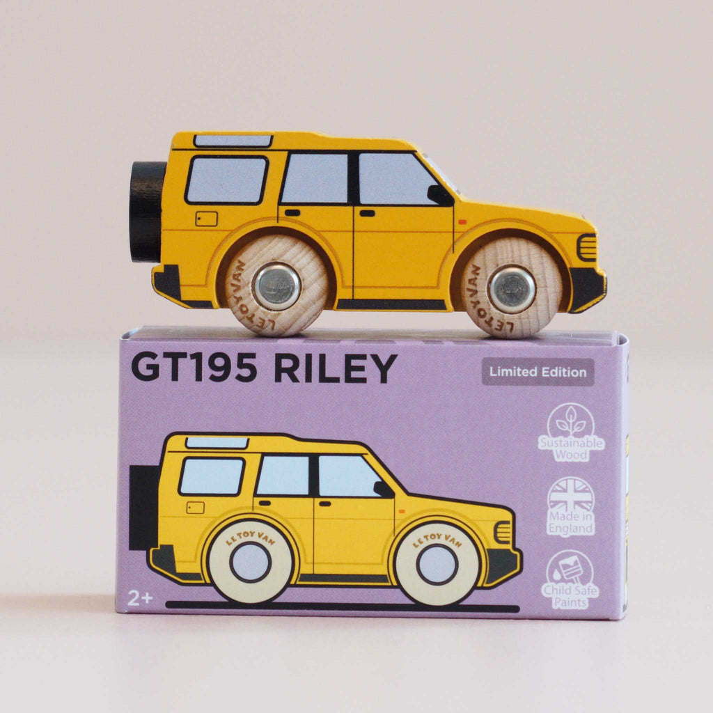 A yellow wooden 4x4 toy SUV rests atop a purple box labeled “No. 35 GT195 Riley | Made in England.” The box features an illustration matching the adventure vehicle, along with icons for sustainable wood, made in England, and child-safe paints.