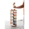 A child plays with the Pound A Ball Tower, a wooden marble run toy featuring a spiral rainbow track and vibrant pieces. The child's hand grips a mallet, ready to hit a ball at the top of the toy. Crafted from non-toxic materials, it enhances motor skills in a gently illuminated, serene environment.