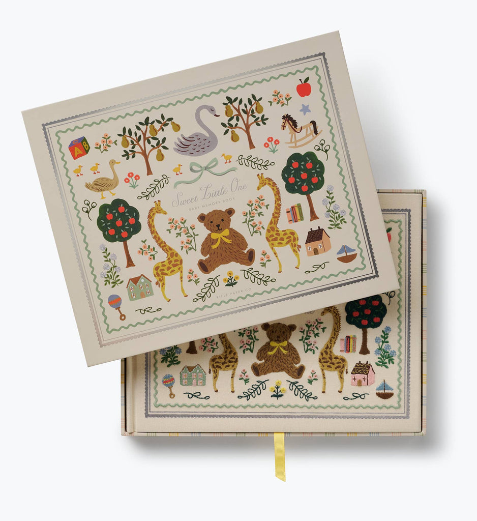 Store your Storybook Embroidered Baby Book or milestone baby book in this charming decorative box, adorned with delightful animal and nature illustrations including a teddy bear, giraffes, swans, trees, and houses. The lid features the phrase “Sweet Little One,” and the box is finished with a yellow ribbon pull tab—perfect for preserving precious memories.