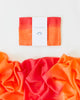 A vibrant playsilk in shades of orange and red, ideal for open-ended play, is neatly folded with a label that reads "Sarah's Silk Giant Fire Playsilk." Below it, the same fabric is spread out to reveal a gradient transitioning from deep red to bright orange against a white backdrop, sparking imaginative play.