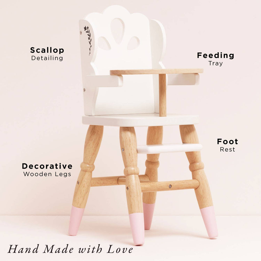 The Dolls Wooden High Chair is a small, eco-friendly wood chair featuring a white seat, scallop backrest, feeding tray, decorative legs with pink tips, and footrest. Perfect for pretend play. Text: "Hand Made with Love.