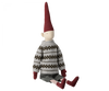 A Maileg Christmas Mega Pixy - (Size 6) with a long red hat, white and gray patterned sweater, and striped socks, sitting isolated against a black background.