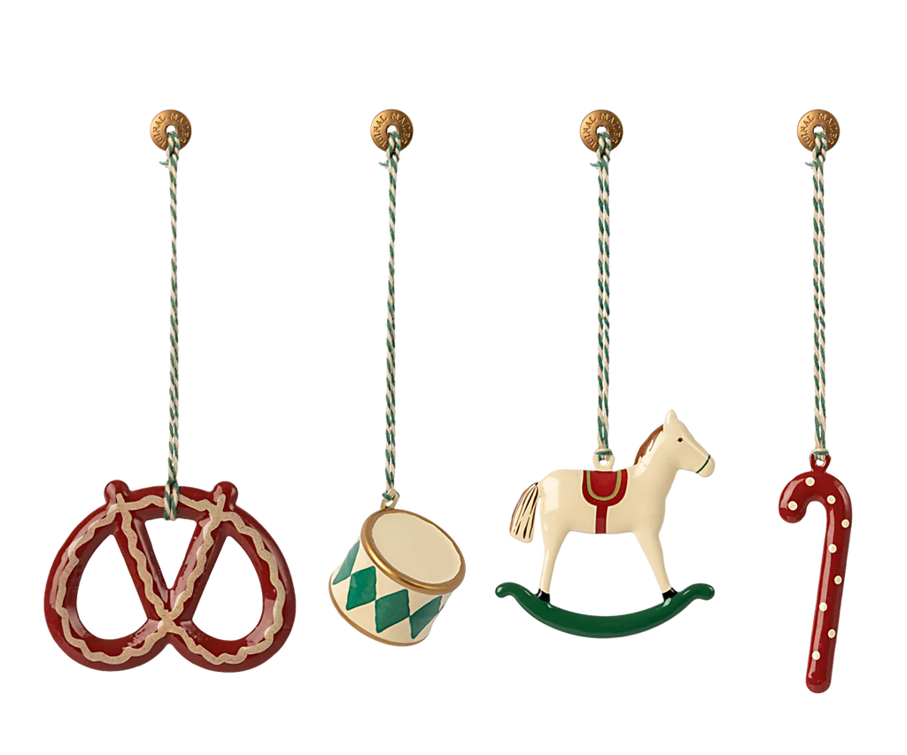 The Maileg Peter's Christmas Ornament Set (2024) features four delightful ornaments on striped strings: a red pretzel, a green and white drum, a white rocking horse, and a red candy cane. Each metal ornament is attached to a small decorative knob, adding a touch of festive charm to any gift box or holiday display.