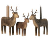 Three Maileg Wooden Reindeer Candle Holders and two candles on a neutral background. The deer, varying in size, depict a family scene with ornate antler details and are sold separately.