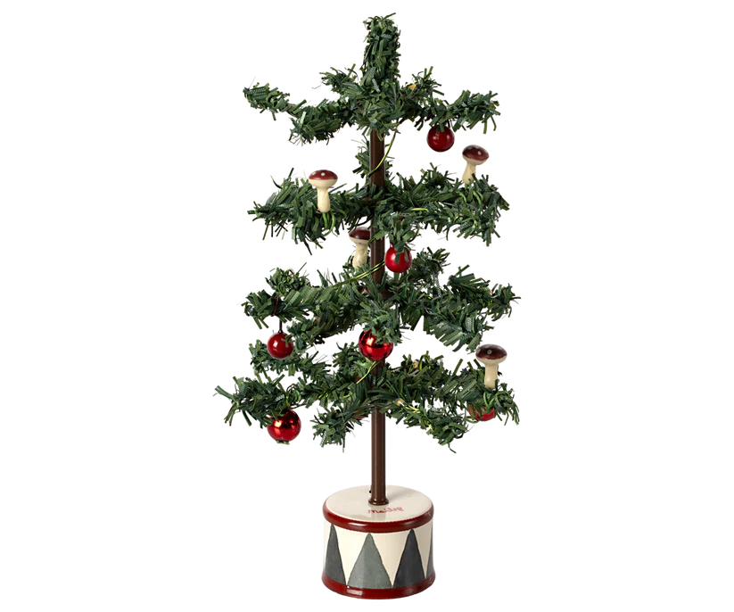 The Maileg Christmas Tree, Mouse is a charming small decorative tree featuring sparse green branches, red berries, and tiny mushroom ornaments. It glows with warm LED bulbs and stands on a round base adorned with a red and white diamond pattern, making it the perfect companion to a festive gingerbread house.