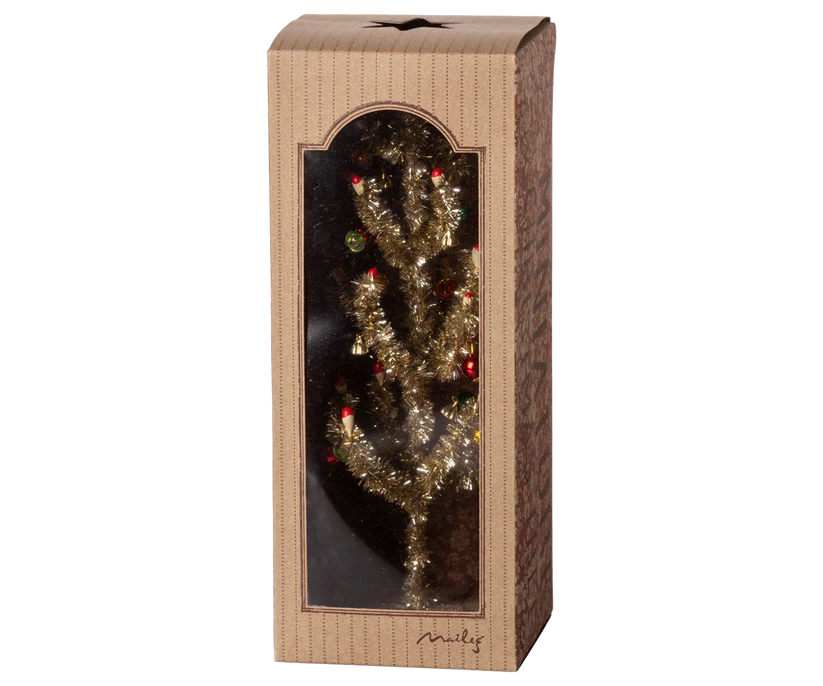 The Maileg Christmas Tree - Gold with Red and Green comes in a brown box with a transparent front, showcasing its small artificial gold design adorned with red and green ornaments. The packaging, ideal for home decoration, features a subtle striped pattern.