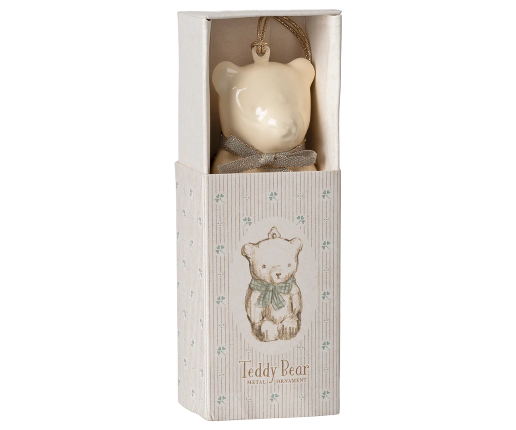 An off white and blue Maileg metal teddy bear ornament featuring handpainted details and a bow, presented in a decorative box adorned with a charming illustration of a teddy bear wearing a scarf. The text on the box reads, "Teddy Bear Metal Ornament.