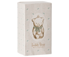 A decorative box showcases a vintage-style illustration of a teddy bear with a green bow, accentuated by hand-painted details. The box is adorned with a subtle striped pattern and small clover-like motifs, featuring the text "Maileg Metal Ornament, Teddy Bear - Off White/Blue" at the bottom, reminiscent of charming Maileg ornaments.