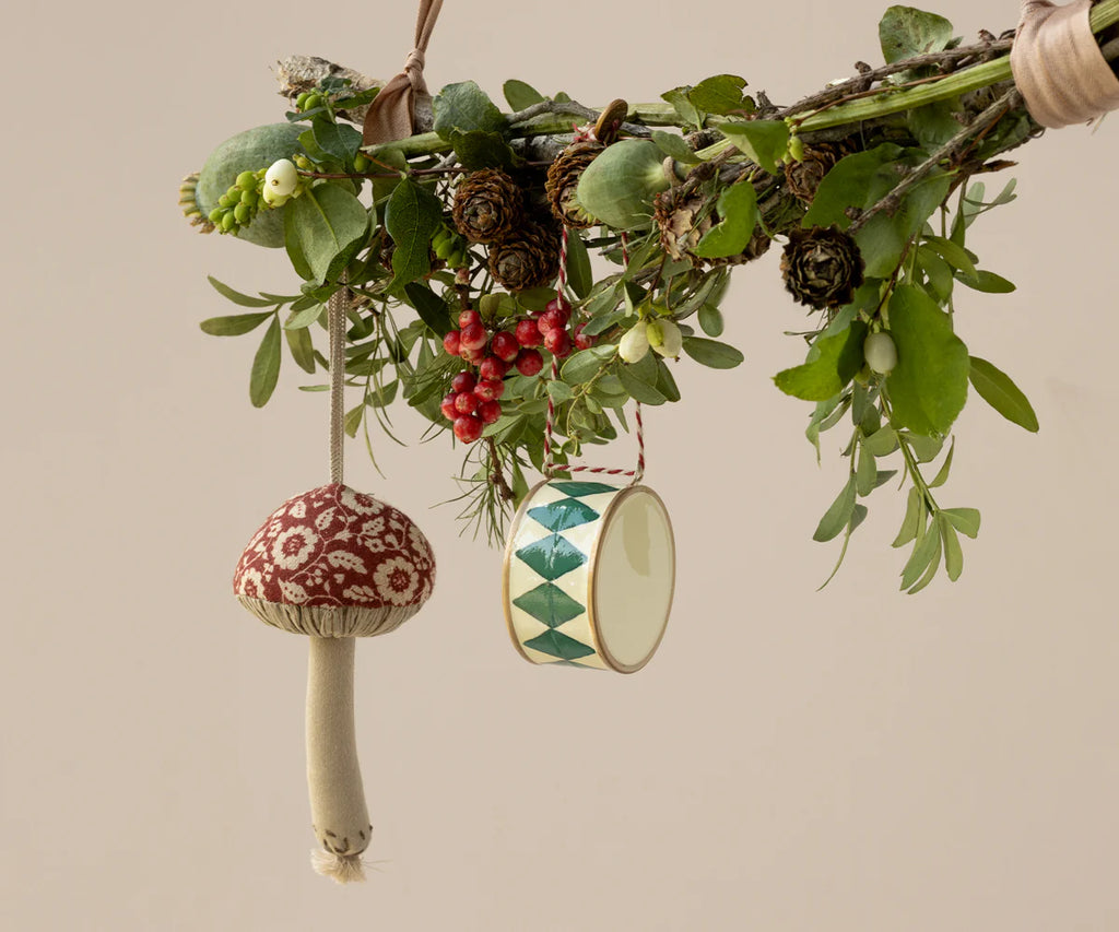 A festive holiday branch decorated with green leaves, red berries, pinecones, and the Maileg Christmas Fabric Ornament, Mushroom - Winter Flower - Red—perfect for adding a unique touch to your Christmas tree.