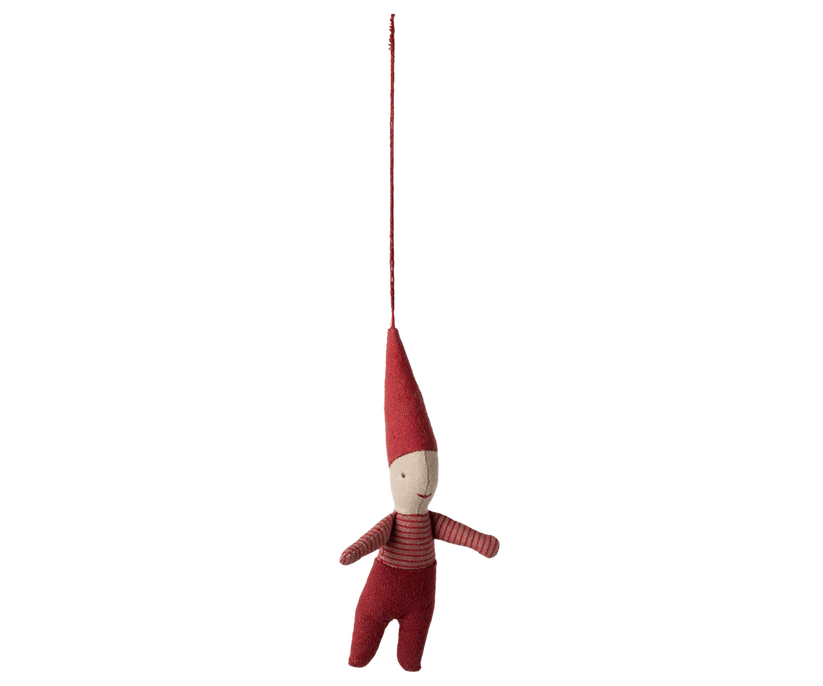 The Maileg Pixy Ornament - Boy features a small plush figure in a red outfit with a pointed hat, hanging from a long, thin red strap. Its simple, smiling face and charming design are set against a plain black background, making it ideal for adding whimsy to your home decor during the holiday season.