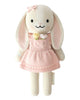 Cuddle + Kind Clover the Bunny (Blossom) is a hand-knit plush bunny in a pink flower dress with a bow on one ear, long floppy ears, black eyes, and a sweet smile—beautifully handmade in Peru under fair trade practices.