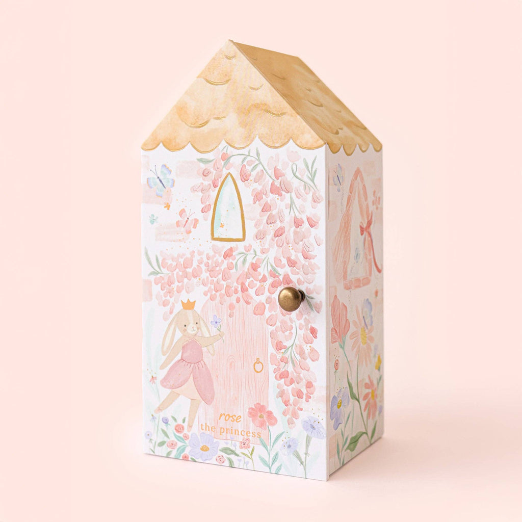 Cuddle + Kind Tiny Rose the Princess: a decorative pastel house-shaped box with floral designs, gold roof, pink-dressed bunny illustrations, and a small round front knob. Fair trade piece.