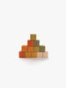 The Sabo Concept Mini Wooden Blocks – Flower Meadow set features a small pyramid built from 10 colorful wooden blocks arranged in four layers, showcasing beautiful shades of orange, yellow, green, and beige on a plain white background. This educational toy is perfect for nurturing children’s fine motor skills through creative play.