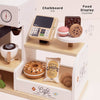 The Barista Café Shop playset (ships in one week) features a chalkboard till, food display counter, wooden coffee machine, pastries, cookies, chocolate, donut, chips, and a coffee cup on white and wood shelves for imaginative pretend play.