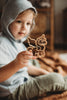 A child in a light blue hoodie closely examines the Unicorn Cutter Set - Eco Playdough Tool indoors—ideal for sensory play or combining with other eco-friendly playdough tools.