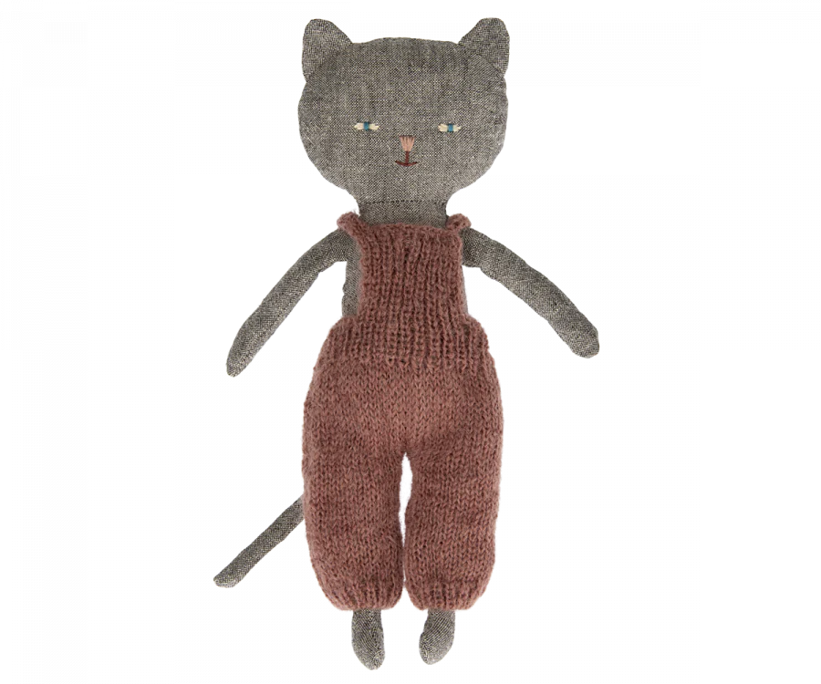 A handmade knitted Maileg Cat Stuffed Animal from the Best Friends collection, with a gray head, green eyes, and wearing a rust-colored jumpsuit, isolated on a white background.
