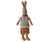 A soft natural linen rabbit with long ears stands upright. It is dressed in a knitted, blue and white striped sweater and brown pants. The bunny's wardrobe boasts a simple, minimalist design with a neutral expression, making it a charming addition to any Maileg Rabbit Size 1 - Brown - Shirt And Shorts dollhouse.