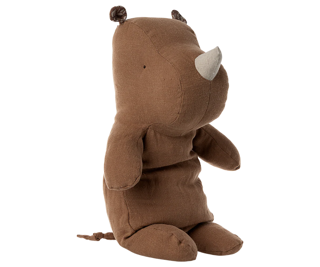 A Maileg Rhino, Medium - Chocolate plush toy with small ears, a short horn, and a tail, made from soft fabric, sits upright against a plain white background.