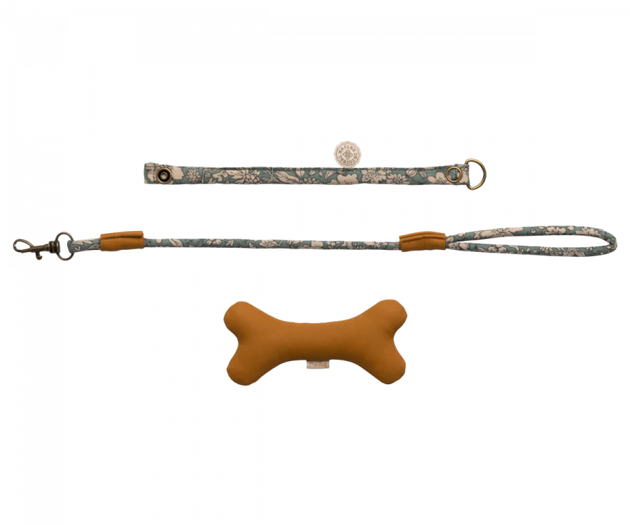 The image showcases a Maileg Puppy Accessories - Blue featuring a turquoise print with silver accents, complemented by a brown, bone-shaped dog toy.
