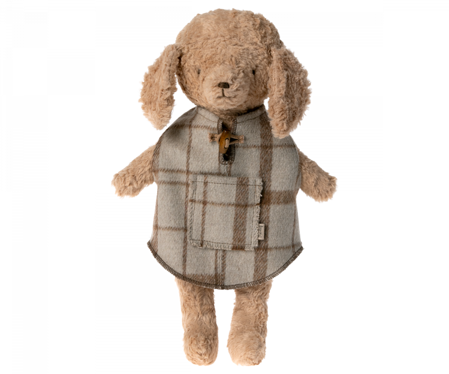 A Maileg Puppy Poncho is wearing a knitted sweater with a pocket and toggle button. The bear has floppy ears, soft textured fur, and even sports a small tail hole, giving it a cute and cozy appearance.