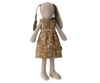 A Maileg Bunny, Size 2 - Flower Dress is dressed in a floral-patterned brown dress, crafted from soft natural fabrics. The bunny has long ears that hang down and a simple embroidered face. The dress features white flowers and leaves, giving it a vintage look. Made with recycled polyester, the toy stands upright with arms and legs extended.