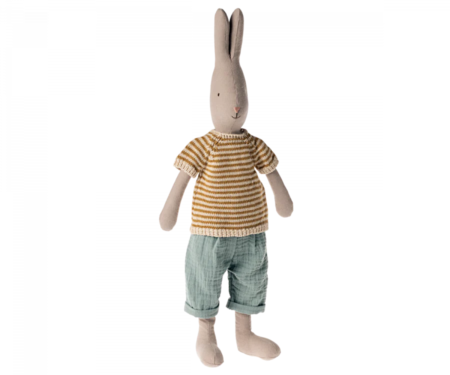 A Maileg Rabbit Size 3, Classic - Knitted Shirt and Pants stands upright, proudly showcasing its place in our clothes collection with a striped yellow and white knit shirt and light blue pants. The rabbit, made of soft natural fabrics, features long ears, a simple embroidered face, and a neutral-colored body.